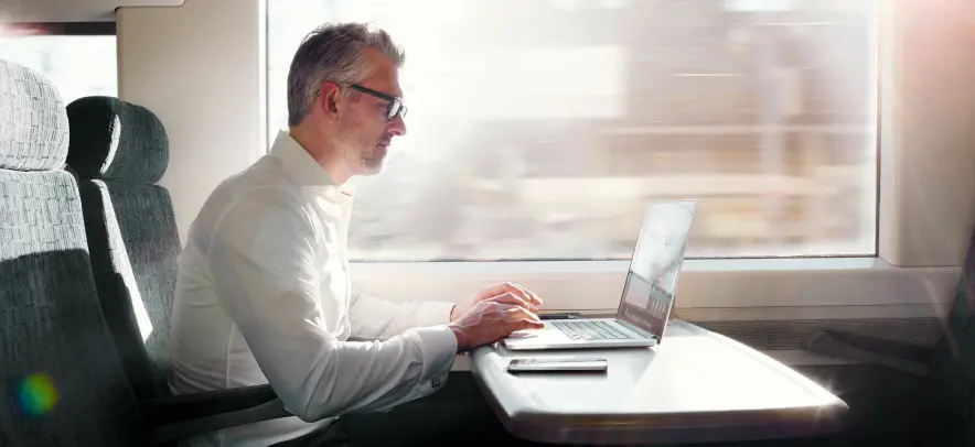 Ein Mann arbeitet auf einer Zugfahrt am Laptop